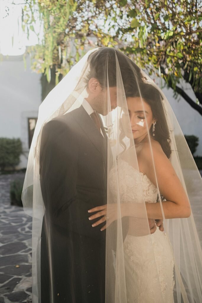 A romantic outdoor wedding portrait of a couple under a veil in San Miguel de Allende, Mexico.